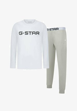Biała koszula z długim rękawem z czarnym logo "G-STAR", w połączeniu z jasnoszarymi spodniami dresowymi z dopasowanym paskiem i ściągaczami na nogawkach.
