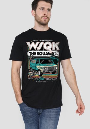 Mann trägt ein schwarzes T-Shirt mit buntem Vintage-Radio- und Van-Motiv, Text "WSQK The Squawk 94.5 FM Hawkins New Hitmaker."