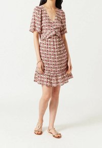 Knee-length klänning i mönstrad tyg med rosa, vita och gröna diamanter, med korta ärmar, volangkant och bälte.