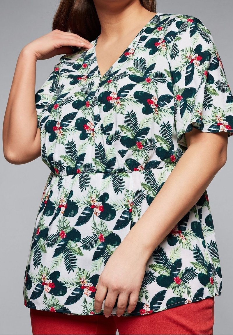 Blouse blanche à manches courtes, ornée d'un motif de feuilles tropicales vertes et de fleurs rouges, avec un col en V et un détail de taille froncée.