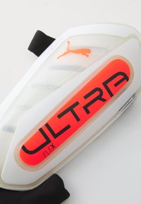 Puma Ultra Flex Schienbeinschoner mit einem klaren Kunststoffkörper, kühlem roten "ULTRA"-Logo und strukturierter Oberfläche sowie einem schwarzen Riemen.