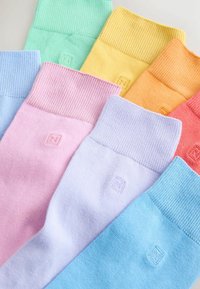 Calcetines de algodón en colores pastel: azul claro, rosa, lavanda, menta, amarillo, naranja y rojo. Puños acanalados con pequeño detalle de logo en relieve.