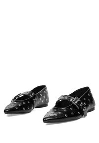 Bailarinas de cuero negro con punta afilada, con tachuelas metálicas y una correa cruzada. Textura suave con un tacón bajo.