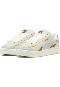 Lichtbeige suède sneakers met een blauwe leren accent en bruine details, voorzien van witte veters en een getextureerde rubberen zool.