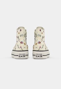 Sapatilhas de lona de cano alto em off-white com bordados florais coloridos, sola de borracha preta e a proeminente marca "CONVERSE ALL★STAR".