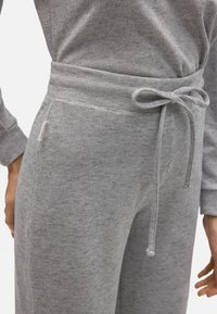 Joggers de algodón gris con cinturilla elástica, acompañados de un cordón ajustable, bolsillos laterales y un acabado texturizado para mayor comodidad.