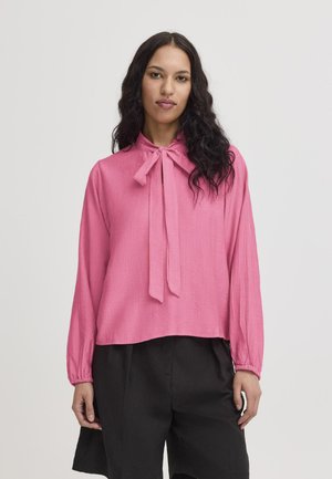Pink blouse with a tied neck, long sleeves, and a textured fabric. Pairing with black trousers, offering a relaxed fit.