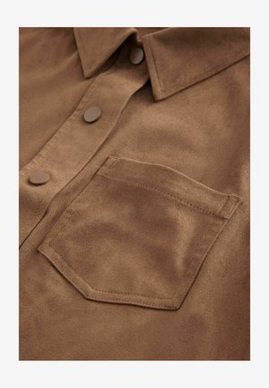 Chemise en daim brun avec un col pointu, une poche avant et deux boutons ronds. Texture douce avec une finition mate.