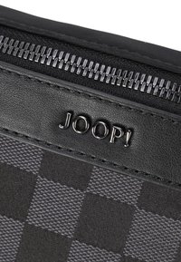 Czarny, teksturowany woreczek w kratę, z metalicznym zamkiem błyskawicznym i wytłoczonym logo "JOOP!" na gładkim skórzanym pasku.