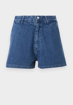 Sinised teksapüksid kõrge vöökohaga, nööpidega kinnitusega, vööaugudega ja lühikese äärega, taustal tavaline sissevõte.