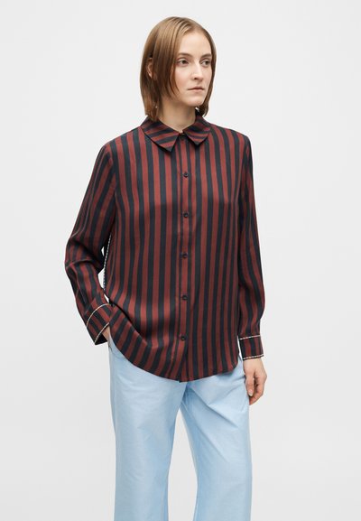 Sötétvörös és fekete, függőleges csíkos ing, hegyes gallérral és hosszú ujjakkal, amelyek kontrasztos mandzsetta-díszítéssel rendelkeznek.