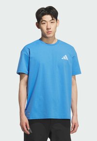 T-shirt di cotone blu con scollo tondo e maniche corte, con un logo a tre strisce bianche diagonali sul lato sinistro del petto.