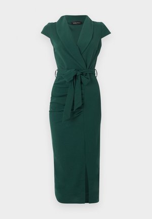 Robe midi sans manches vert foncé avec col châle, nœud de ceinture à la taille et fente avant sur un fond clair uni.