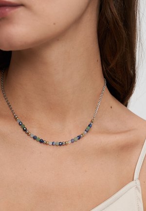 Perlenkette mit mehrfarbigen Edelsteinen und goldenen Akzenten, auf einer feinen Silberkette aufgelegt. Für eine enge Passform um den Hals geformt.
