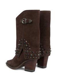 Botas de tobillo de ante marrón con un tacón bajo. Presentan adornos de metal plateado, una hebilla lateral y embellishments con tachuelas en varias formas a los lados.