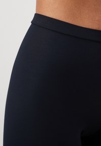 Marina leggings med en mjuk, elastisk tyg och en bred midjeband. Ytan är solid med en lätt glans, vilket betonar komfort.