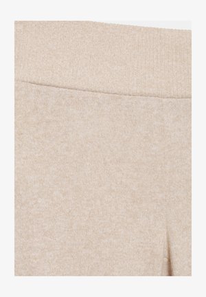 Prim-plan cu pantaloni bej tricotati, prevăzuți cu talie elastică zimțată și material texturat moale.