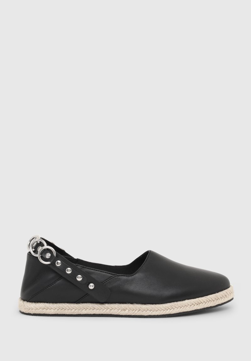 Espadrille en cuir noir avec une semelle plate, ornée d'un contour en jute tressé, d'une sangle réglable avec des accessoires en argent et de détails perforés.