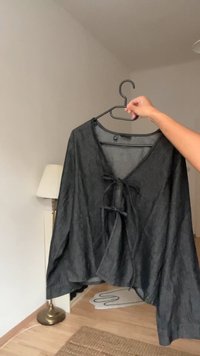 Svart, lätt blus med V-ringning och knytning fram. Draperad design med korta ärmar och avslappnad passform. Texturerat tyg.