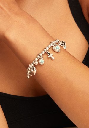 Pulsera de plata con cuentas redondas y dijes que incluyen un corazón, una cruz y un símbolo de paz con detalles en turquesa.