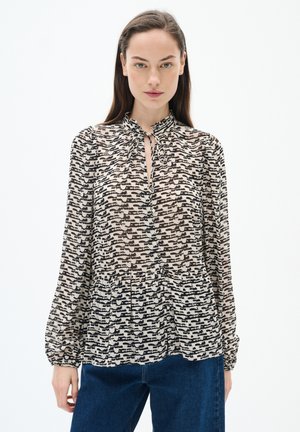 Blusa a maniche lunghe in beige con un motivo astratto nero, caratterizzata da un colletto a chiave e dettagli arricciati attorno al colletto.