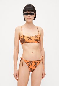 Pomarańczowy bikini z czarnymi kwiatowymi wzorami, z prostokątnym górami i niskimi dolnymi częściami związanymi po bokach. Gładki, lekki materiał.
