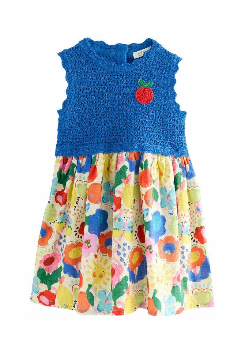Bodice bleu au crochet avec des bords en vagues et une appliqué de pomme rouge ; jupe en coton à imprimé floral coloré avec divers motifs vibrants.