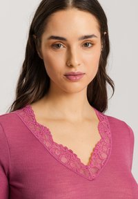 Top aderente a costine in magenta con scollo a V in pizzo. Il pizzo testurizzato presenta un motivo floreale, aggiungendo dettagli al design.