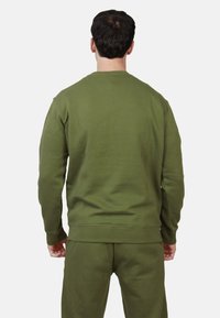 Felpa verde oliva realizzata in morbido misto cotone, con collo a giro, polsini a costine e una vestibilità comoda, abbinata a pantaloni coordinati.