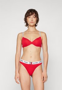 Soutien-gorge rouge et string assorti en tissu doux. Le soutien-gorge possède des coques rembourrées et des bretelles réglables avec des détails de logo.