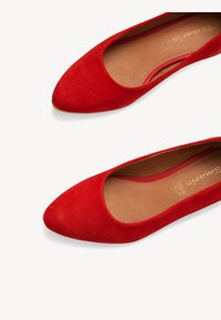 Ballerine in suede rosso con punta affusolata e lati scollati. Texture morbida con una fodera interna liscia. Logo impresso nella soletta.