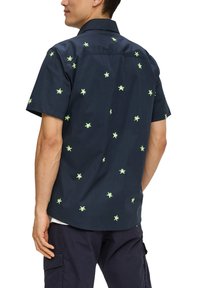 Korte mouwen marineblauw shirt met een kleine groene palmboom borduring, button-down kraag en een afgeronde zoom. De stof lijkt glad en lichtgewicht.