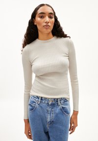 Helles graues, geripptes Langarmoberteil mit Rundhalsausschnitt, kombiniert mit lockeren blauen Jeans, die eine ausgewaschene Optik und Fronttaschen haben.