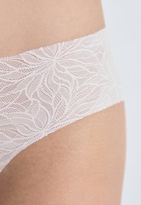 Chiloți hipster din dantelă de culoare roz deschis, cu un model floral pe talie și o textură netedă pe materialul principal.