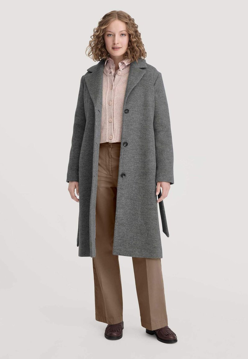 Grauer Wollmischmantel mit Reverskragen, einreihigem Schnitt und fünf Knöpfen. Dazu ein rosa Strickpullover und beige Hose.