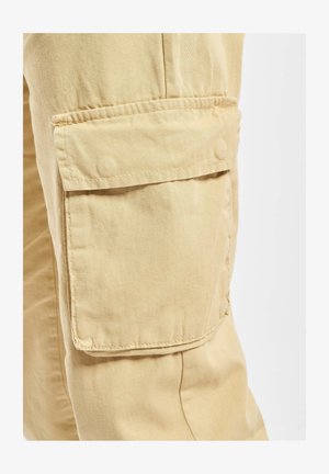 Khaki Cargo-Hosenstoff mit einer auffälligen Seitentasche, die über eine Klappe und einen Druckknopfverschluss verfügt, sowie einer glatten, leicht strukturierten Oberfläche.