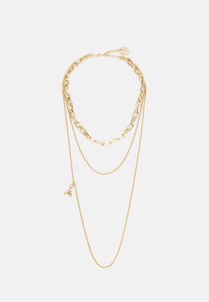 Drie-laags gouden ketting met verschillende schakels en een kleine bij-hanger aan de langste ketting tegen een witte achtergrond.