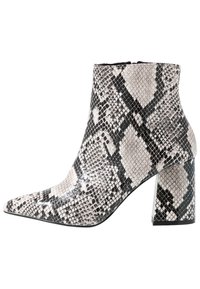 Pointed-toe ankle boot made of faux snakeskin, featuring a black and white pattern, a mid-block heel, and smooth, shiny texture.