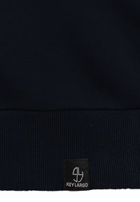 Marineblaue Sweatshirt mit einem gerippten Saum und einer strukturierten Oberfläche, mit einem schwarzen Stoffetikett, das "KEY LARGO" in weißem Text zeigt.