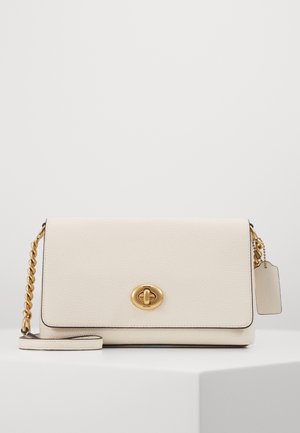 Witte leren crossbody tas met een goudkleurige sluiting, kettinghengsel en hangtag. Heeft een zachte textuur en een gestructureerde rechthoekige vorm.