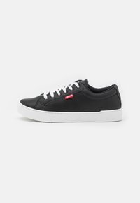 Black leather sneaker with white rubber sole, round toe, and white laces. Features a small red logo on the outer side near the laces.