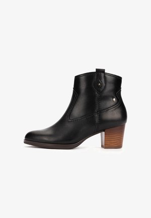 Bottine en cuir noir avec talon bloc en bois, détails de couture latérale et petits clous métalliques sur la partie supérieure, vue de profil.