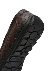 Braunes Leder-Schuh mit gewobener Textur, Gummi-Sohle mit tiefen Rillen und einem kreisförmigen Grip-Punkt, schräger Blick zur Hervorhebung des Designs.