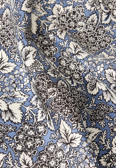 Μαλακό ύφασμα με λεπτομερή λουλουδάτο μοτίβο σε μαύρο και λευκό σε ανοιχτό γαλάζιο φόντο, που δείχνει πτυχώσεις και υφή.