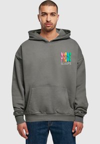 Grauer Kapuzenpulli mit einer frontalen Tasche, der mehrfarbigen Text "PRIDE SCOOPS" auf der linken Brustseite trägt. Weicher Stoff, lässiger Schnitt.