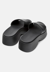 Sandales plateforme noires avec un dessus en cuir lisse, à bout ouvert et une semelle en caoutchouc épaisse et profilée. Design minimaliste sans matériel visible.