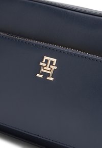 Tumesinist nahast rahakott kuldse embleemiga. Omab luku kinnitust ja siledat tekstuuri täpse õmblemisega servade ümber.