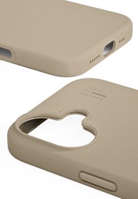 Beige telefonskal lavet af silikone med en glat tekstur. Har en hjerteformet udskæring og hævede knapper for nem adgang. Ideal of Sweden branding.
