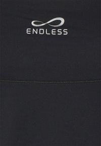 Czarna koszulka sportowa o gładkiej fakturze i srebrnym logo "ENDLESS" na środku, z eleganckim symbolem nieskończoności powyżej.
