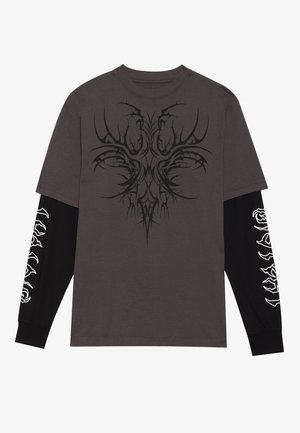 Grå t-shirt med kort ärm har en komplex svart grafisk design på framsidan. Långa svarta ärmar har vita rosor mönster längs sömmarna.